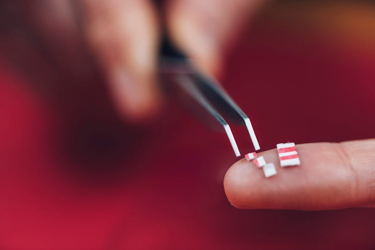 Small or microdoses of LSD cut from a tab sit on a person's finger.