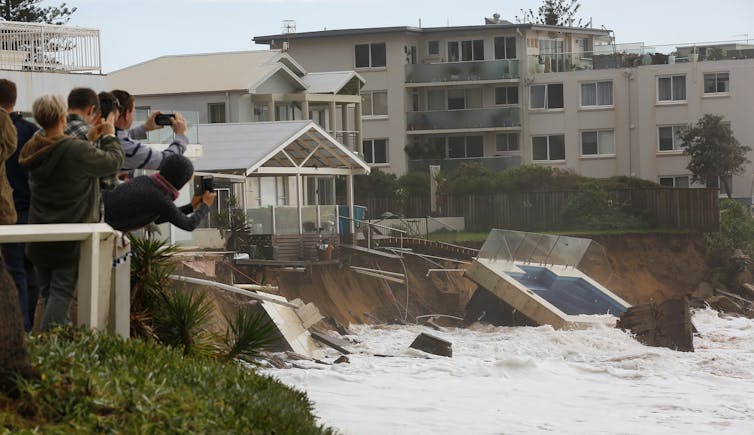 People photograph pool fallen onto beach after storm