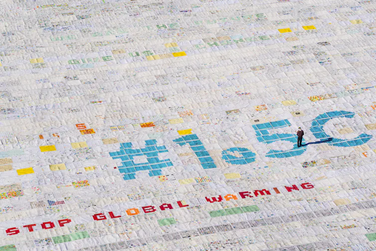 An aerial image of thousands of postcards spelling out '1.5°C stop global warming'.