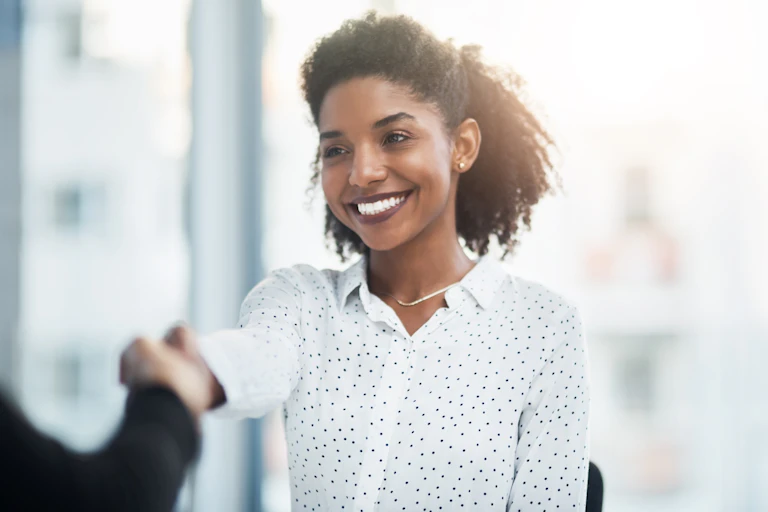 Shot of a young businesswoman with a bright smile shaking hands with a colleague in a modern office.