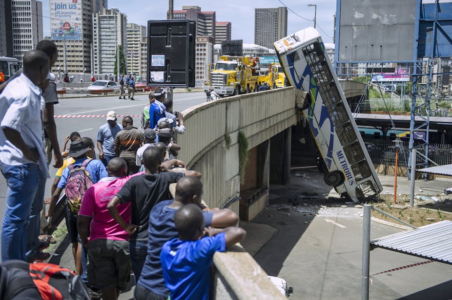 Onlookers gather to look at a bus that drove over the side of the bridge 