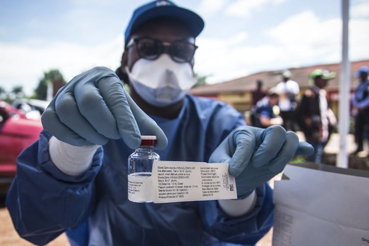 A worker from the World Health Organization (WHO) holds up a vaccination as he prepares to administer it during the launch of an experimental Ebola vaccine in Mbandaka, north-western Democratic Republic of the Congo.