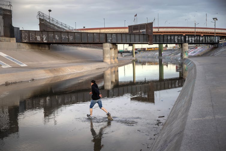 Niño corre a través de un barranco lleno de agua poco profundo