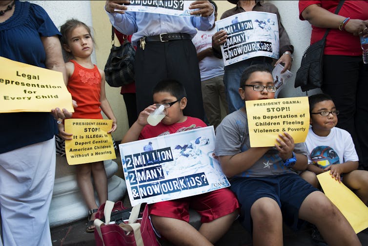 Children hold signs urging the deportation of children to end