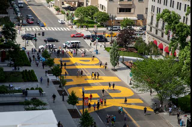 A street close to traffic with the word black painted in giant letters
