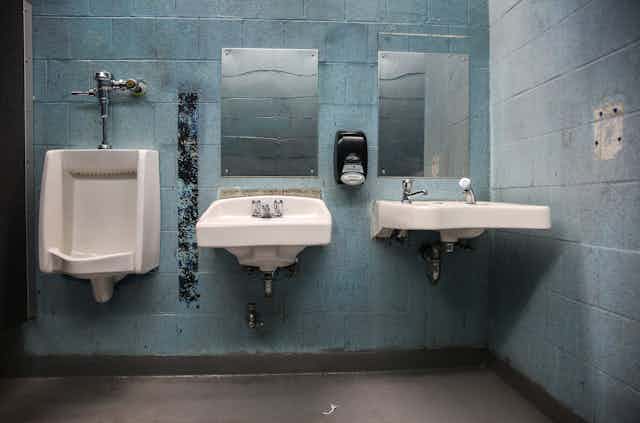 A urinal and two sinks in a rundown public restroom