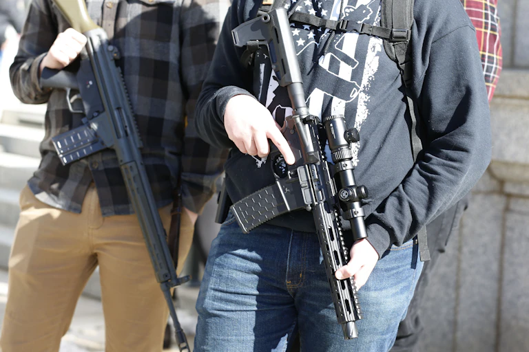 Two people carrying assault-rifle style firearms