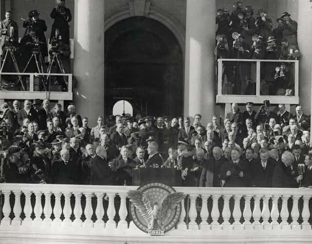 A crowd watches a man on a balcony swear an oath