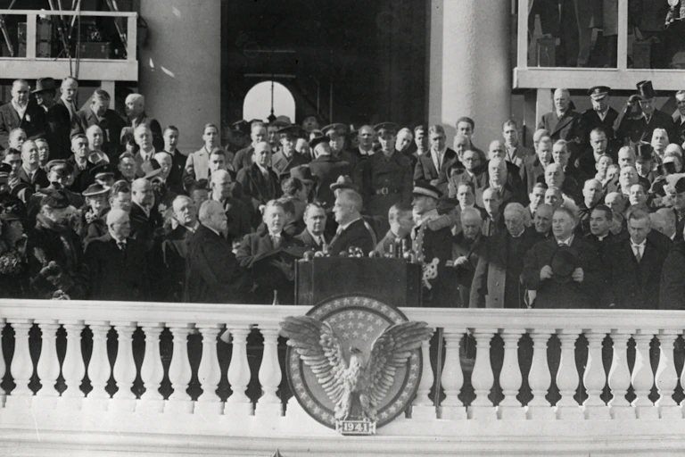 A crowd watches a man on a balcony swear an oath