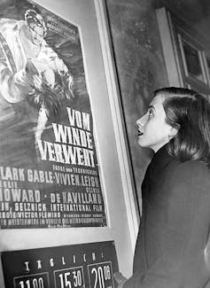 A woman looks at a movie poster of 'Gone with the Wind.'
