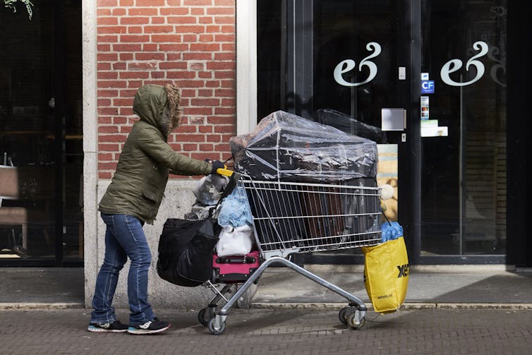 Woman in heavy winter coat pushes a full shopping car