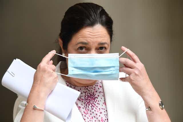Queensland Premier Annastacia Palaszczuk putting on a mask.