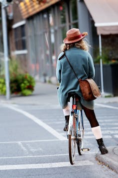 Woman in a hat on a bicycle, shot from behind