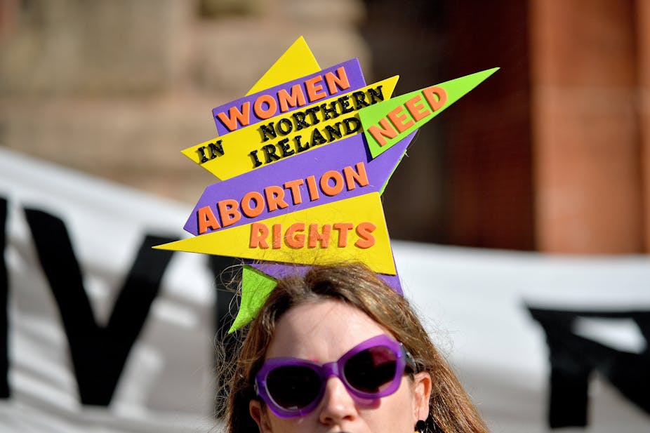 A woman wears a headpiece at a protest that reads 'Women in Northern Ireland need abortion rights'.