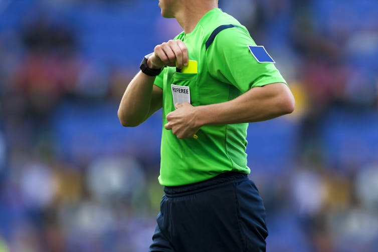 A referee pulling out a yellow card.