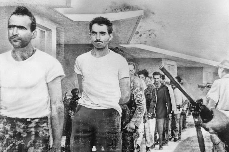 Grim-faced men march under the eye of armed Cuban guards.