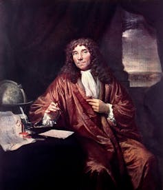 An oil painting of man with long curly hair holding a pair of tweezers posed next to a globe.