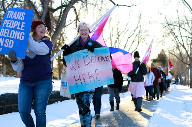 Youth march carrying transgender flags and signs