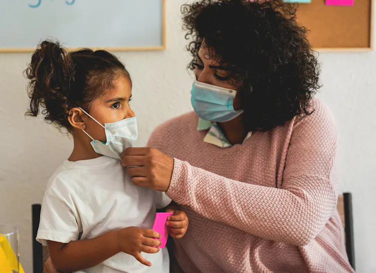 A mother and child putting face masks on.