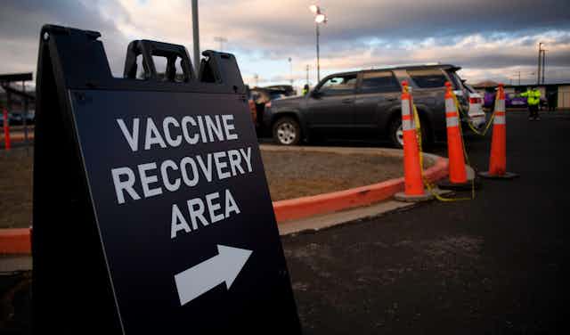 A sign shows the way to a vaccine recovery area.