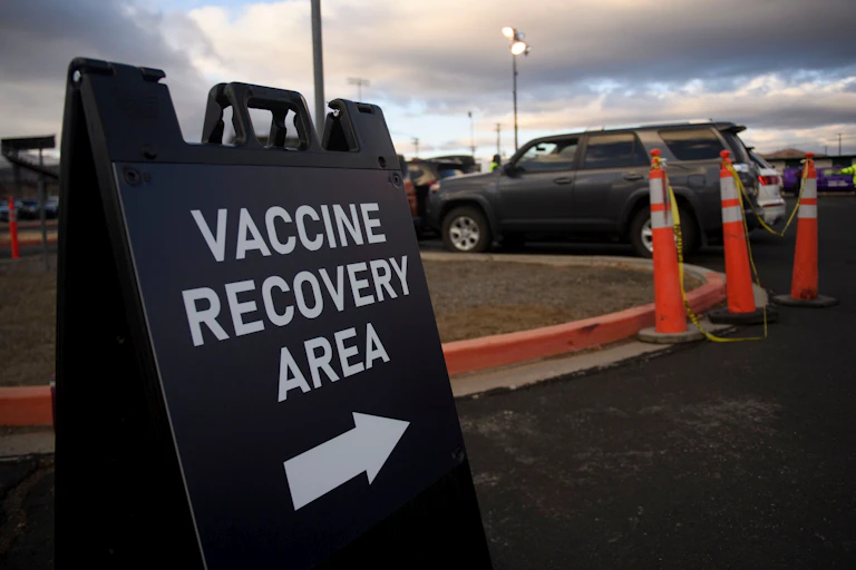 A sign shows the way to a vaccine recovery area.