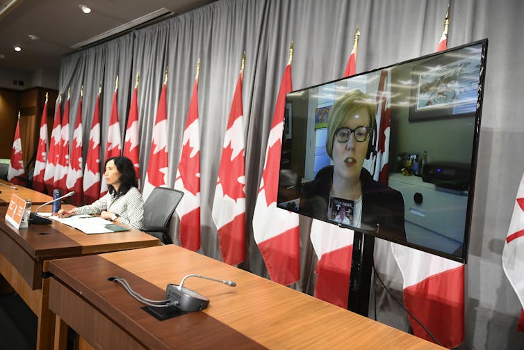 Woman seen on video display at press conference