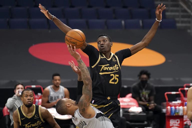Chris Boucher jumps in front of another player with empty stands behind him.