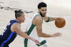 Two men vie for the ball in a basketball game.