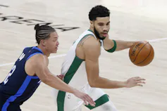 Two men vie for the ball in a basketball game.