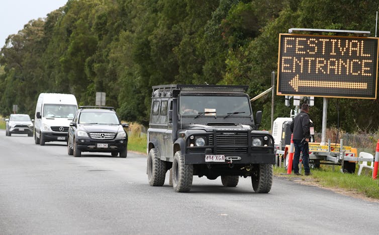 Cars drive away from a sign saying 'festival entrance'.