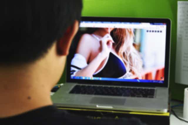Young man looking at sexualised imagery on laptop.