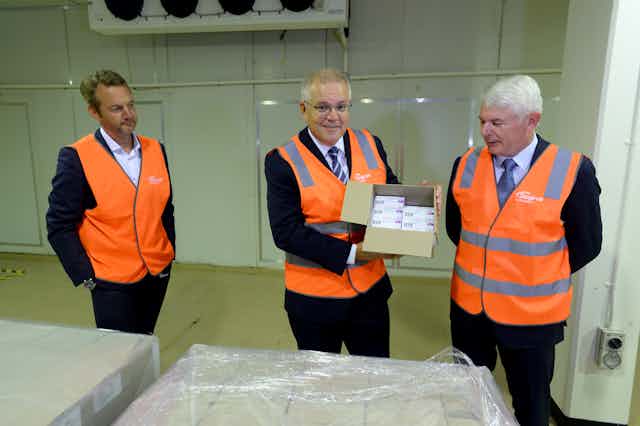 Prime Minister Scott Morrison holding a box full of COVID-19 vaccines