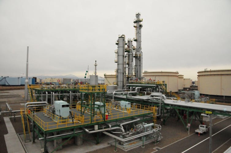 Metal pipes and stacks at a factory site under grey sky.