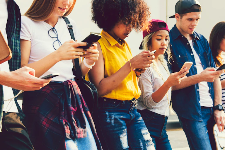 A group of young people of various ethnicity looking at their smartphones