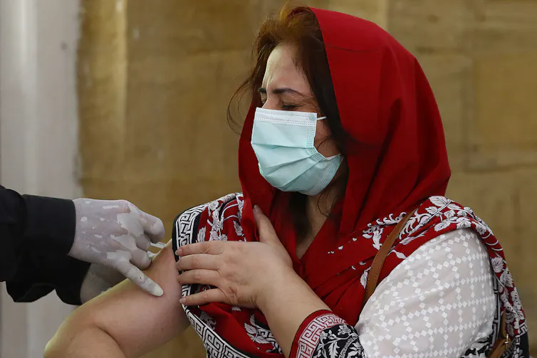 Woman wearing red headscarf receives COVID-19 vaccine