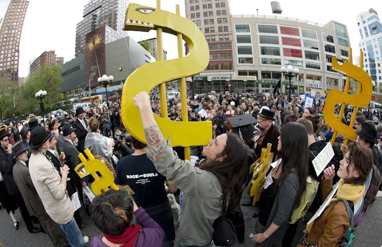 A man holds up a dollar sign during a rally against the high cost of college tuition in New York in 2012.