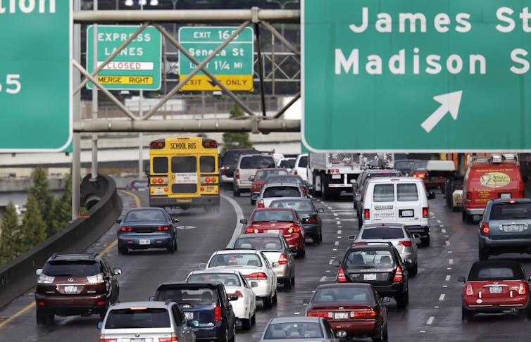 Heavy traffic moves along an interstate highway in Seattle with large signs directing cars to various offramps