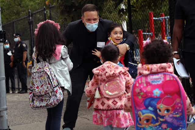 A mayor interacts with a group of schools girls wearing masks.