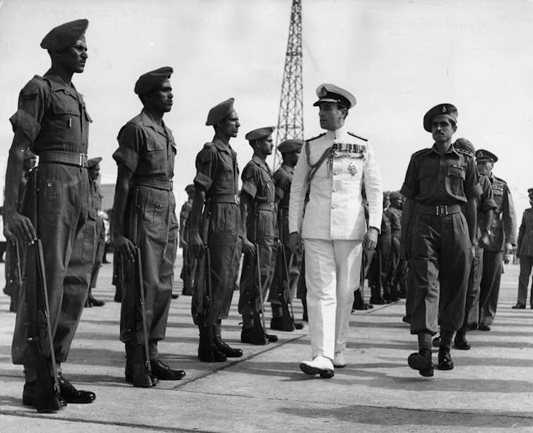 Black-and-white image of Indian soldiers saluting a British man in white military dress