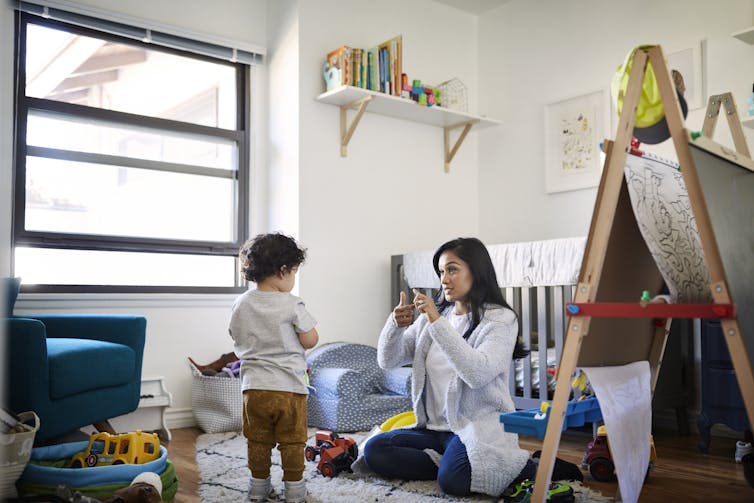 A woman teaching a child sign language.