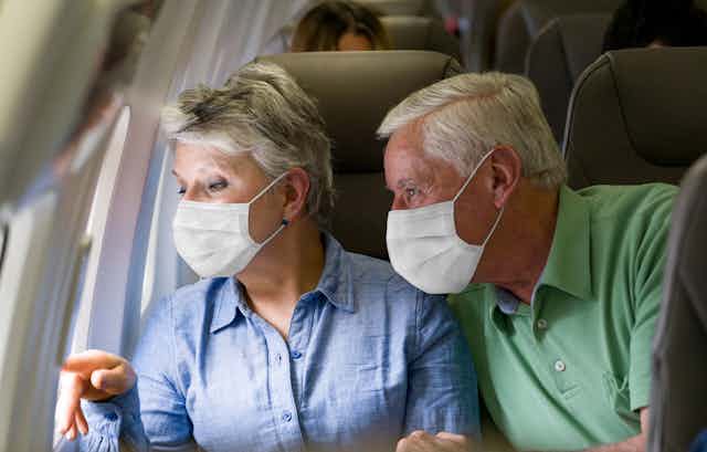 A older couple wearing masks in a airplane. 
