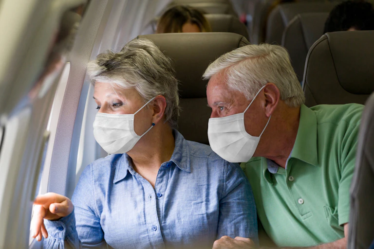 A older couple wearing masks in a airplane.