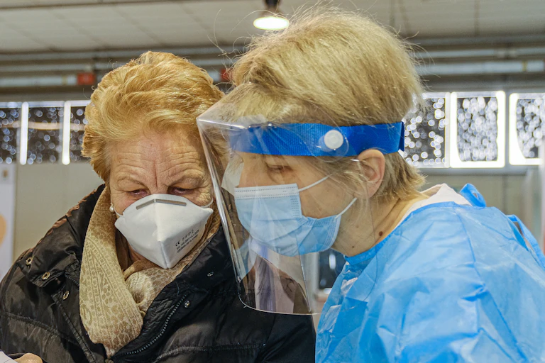 A woman wearing a mask with a doctor wearing a mask and shield.