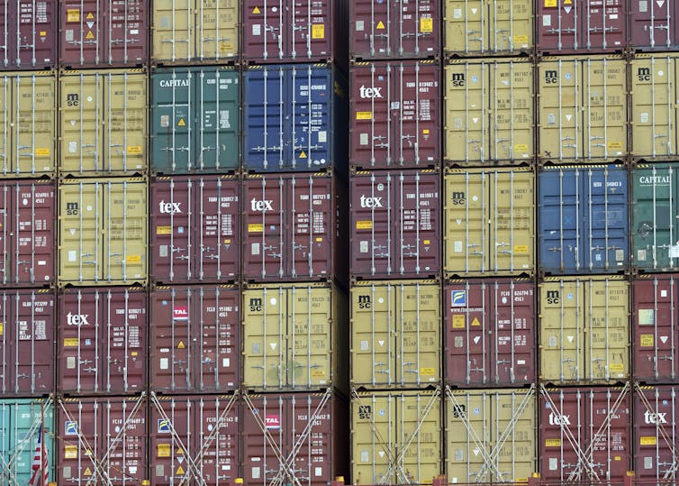 Stacks of shipping containers of various colors sit on an out-of-view ship at a port in Georgia