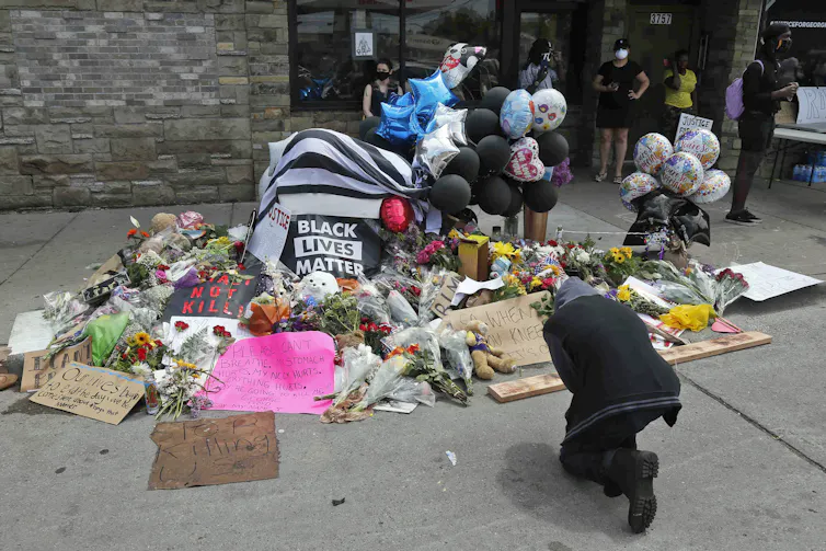 People gather and pray around a makeshift memorial honouring George Floyd.