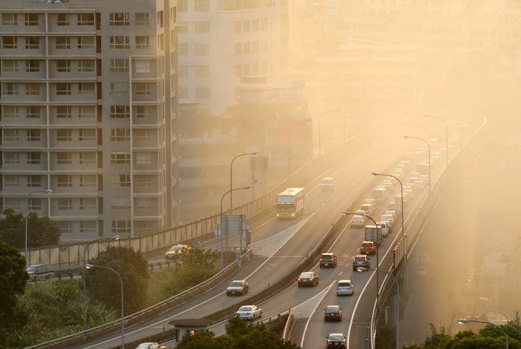 cars drive along a highway in a city masked by smog