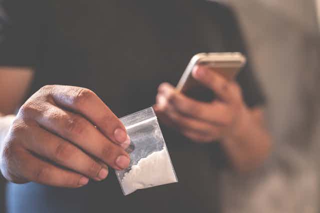 Man holding a small bag of cocaine