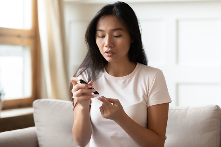 A woman tests her blood sugar by pricking her finger.
