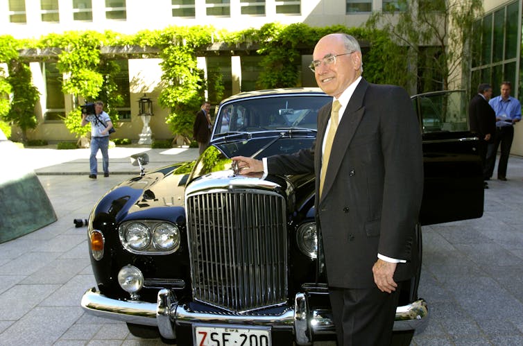 John Howard in front of a Bentley
