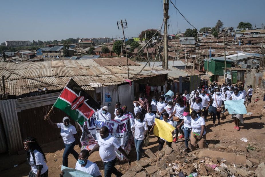 Human rights defenders wave flags and signs as they march through Kibera slum